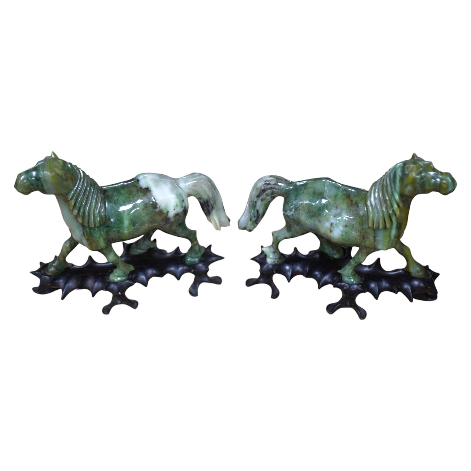 A pair of mid 20th century Chinese jadeite figures of horses, raised on hardwood stands, 13cm wide. Condition - fair, two legs broken and re-glued